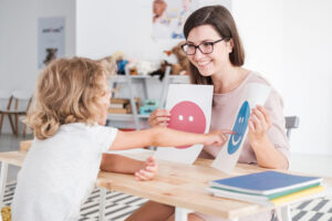 Child in ABA therapy pointing to happy face