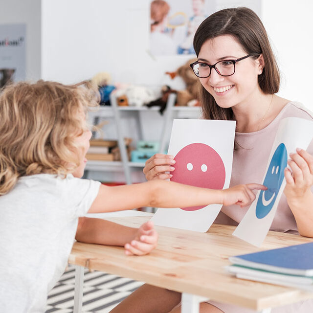 Child in ABA therapy pointing to happy face