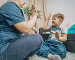 Young boy high-fiving therapist in ABA session